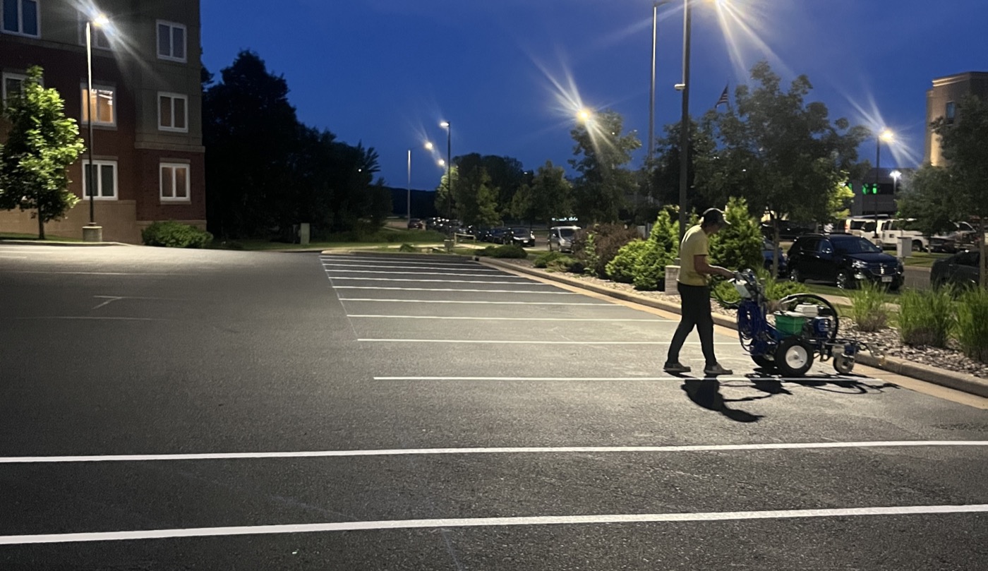 A contractor striping a parking lot at night